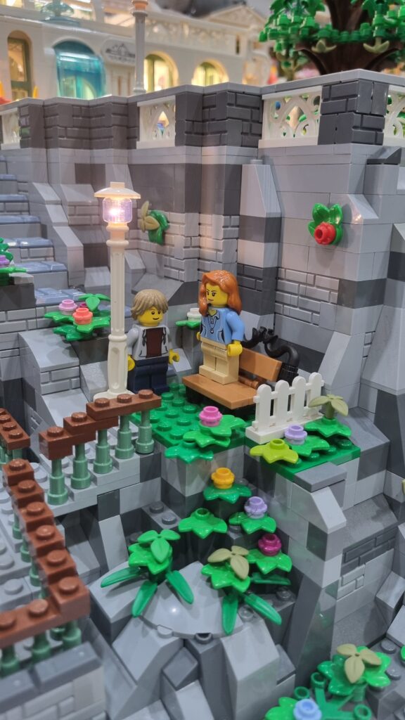 Due minifigure accanto a una panchina e a un lampione acceso sulla terrazza.